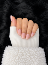 Hélène glossy light nude pink round press on nails, hand pose with white sweater cuff – Nailora Paris
