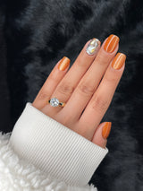 Ambre press on nails — amber shimmer with crystal accent, hand shot close-up