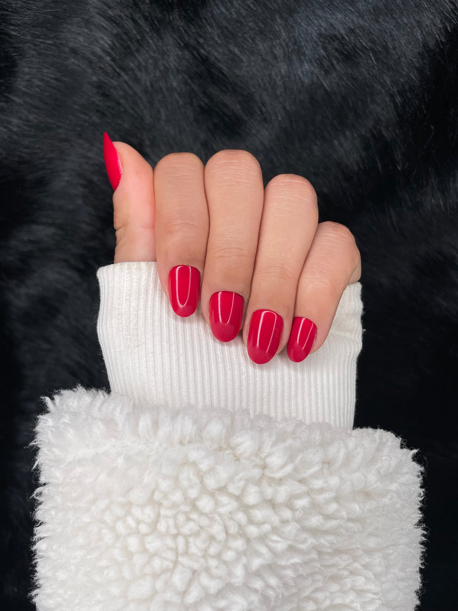 Valentine cherry red medium round fake nails — fist pose showing glossy finish